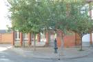 Una de las plazas del pueblo con el edificio de las antiguas escuelas al fondo, pequeña fuente y árboles ornamentales